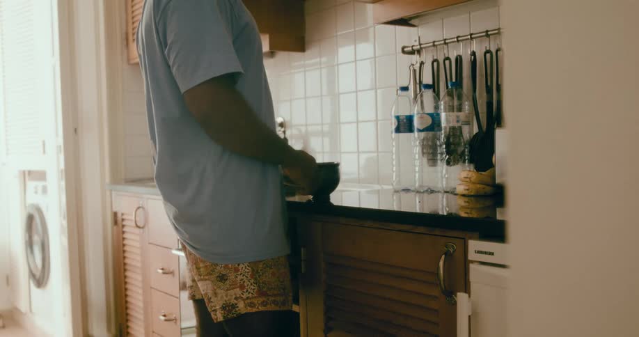 Man makes tea using an electric kettle and a tea bag while standing in the kitchen