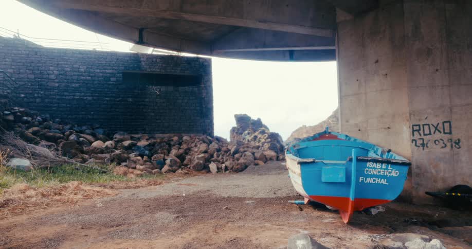 Blue and white wooden boat moored under a viaduct