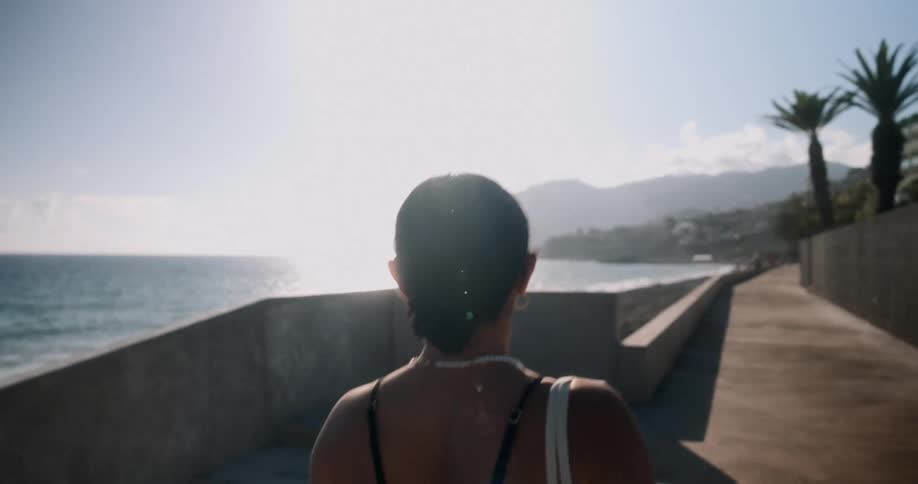Back view of a woman walking on a seaside sidewalk