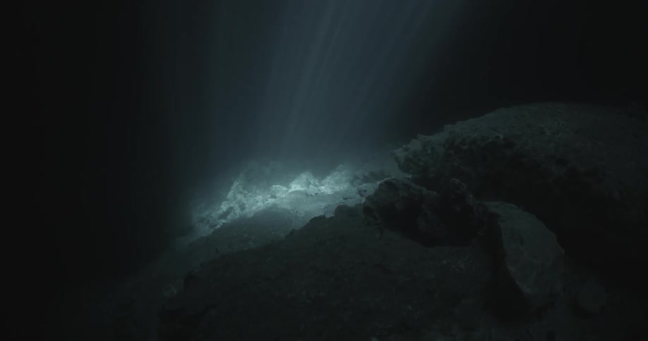 Light shines on the rocks in the dark water below