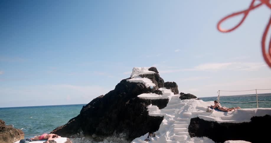 Two women lying on white sand on a rock by the sea