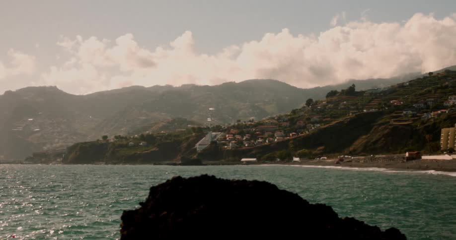 Landscape of a beach surrounded by mountains with urban buildings