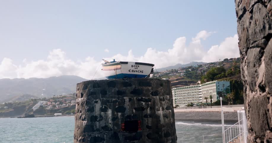 Rocky viewpoint with a wooden boat on top overlooking a beach landscape
