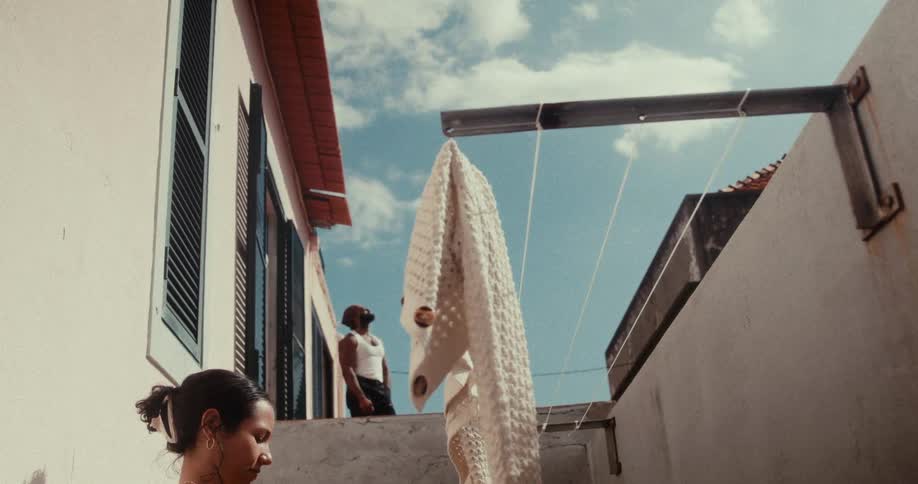 Man standing on a porch and a woman standing next to a clothesline in the backyard