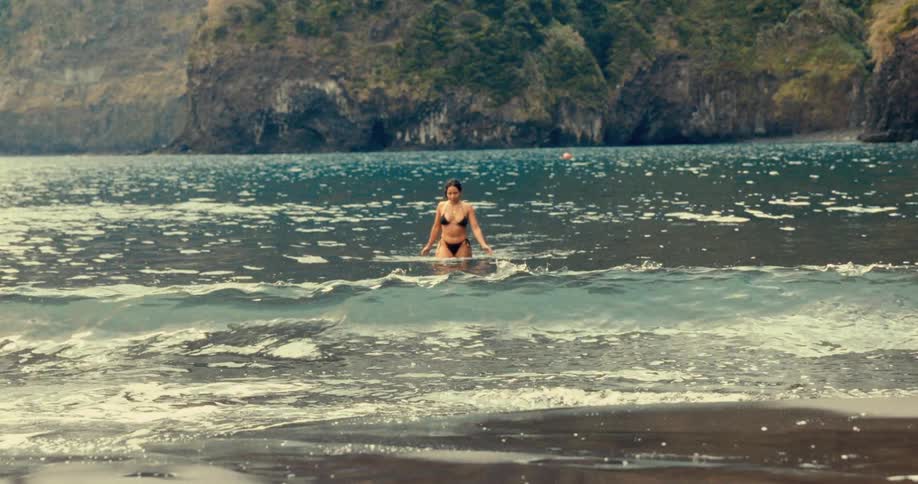 Woman in black bikini coming out of the sea