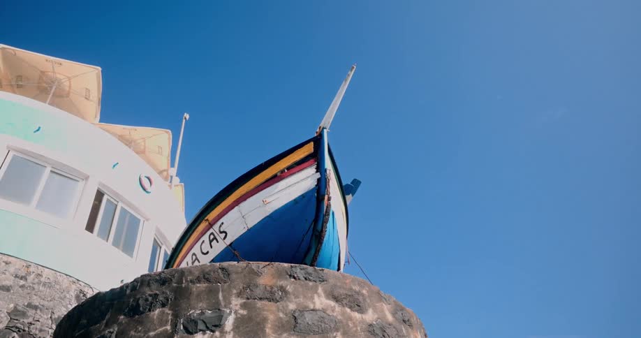 Colorful boat on top of a rocky surface with a building in the background