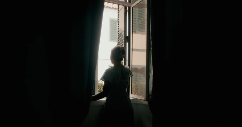 Woman opening the window of a dark room