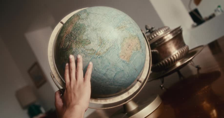 Hand rotating a globe on a table