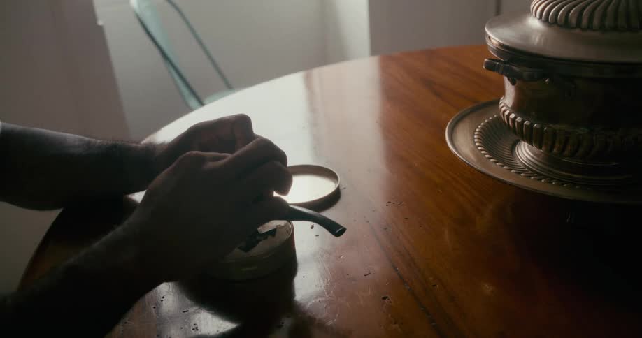 Pair of hands preparing a pipe on the table