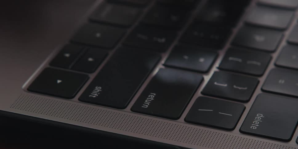 A close up of fingers typing on a laptop keyboard