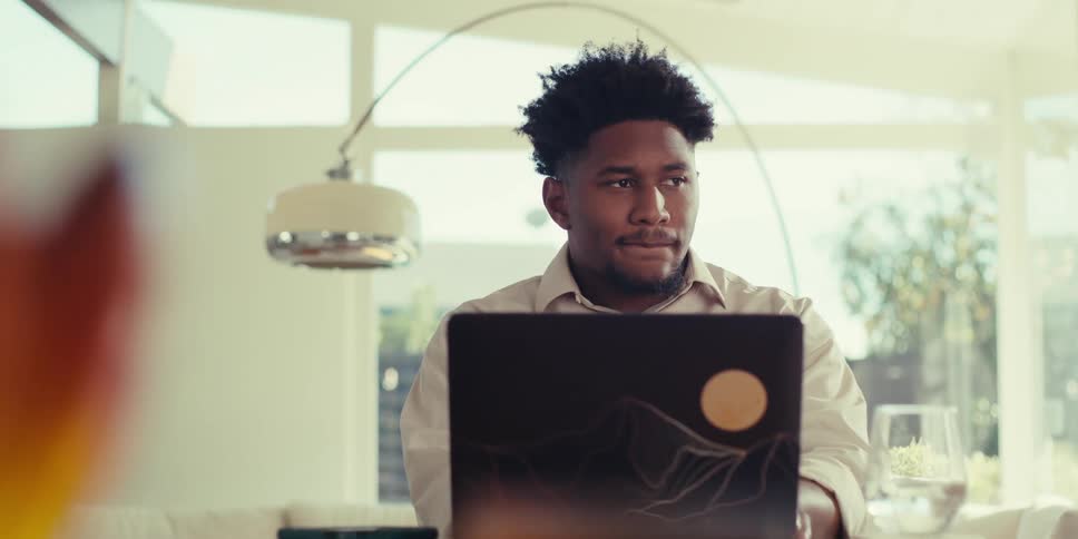 Man wearing a brown shirt works on the laptop at the table