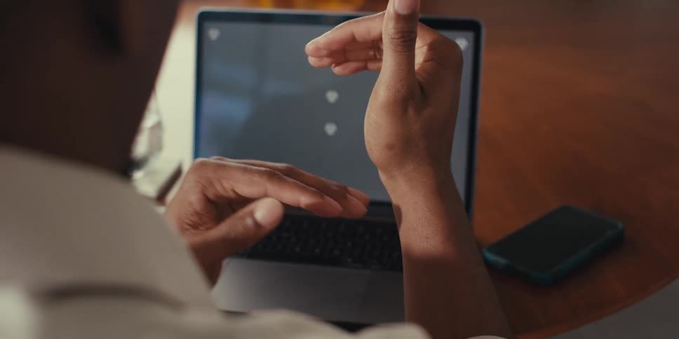 Pair of hands of a man gesturing towards a laptop