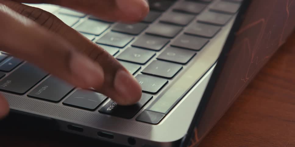 Closeup of an adult hand typing on a laptop keyboard