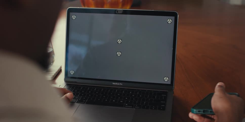 Hand interacting with a smartphone and an open laptop in front