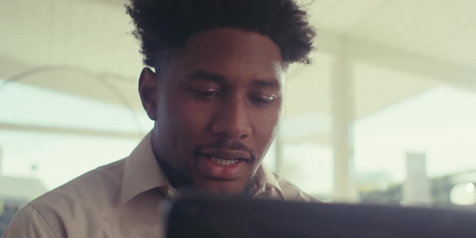 A man in a brown shirt becomes excited during a video call in his living room