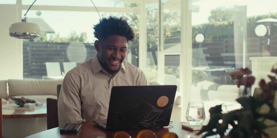 Man sitting at a table in front of a laptop in an indoor space of a house