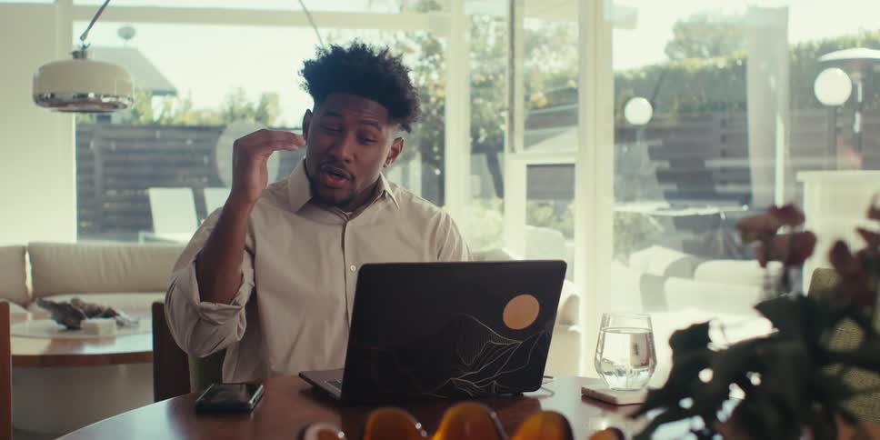 Man talking and explaining something with hand gestures in front of a laptop