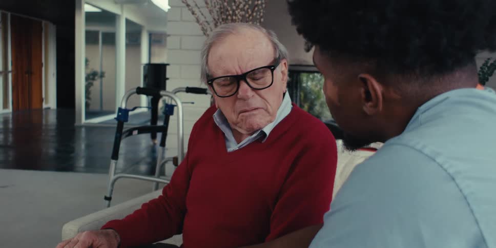 Nurse next to an elderly gentleman sitting together on a sofa talking