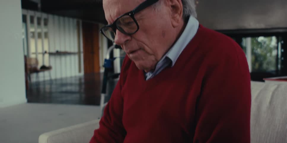 Home care professional shows a tablet to an elderly senior citizen while they sit in the living room