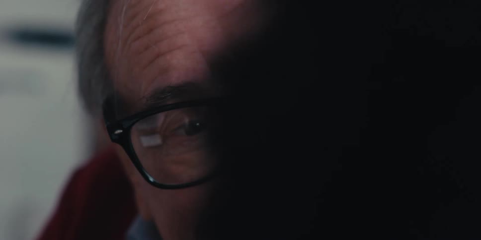 Portrait of an elderly man with glasses talking to a person next to him