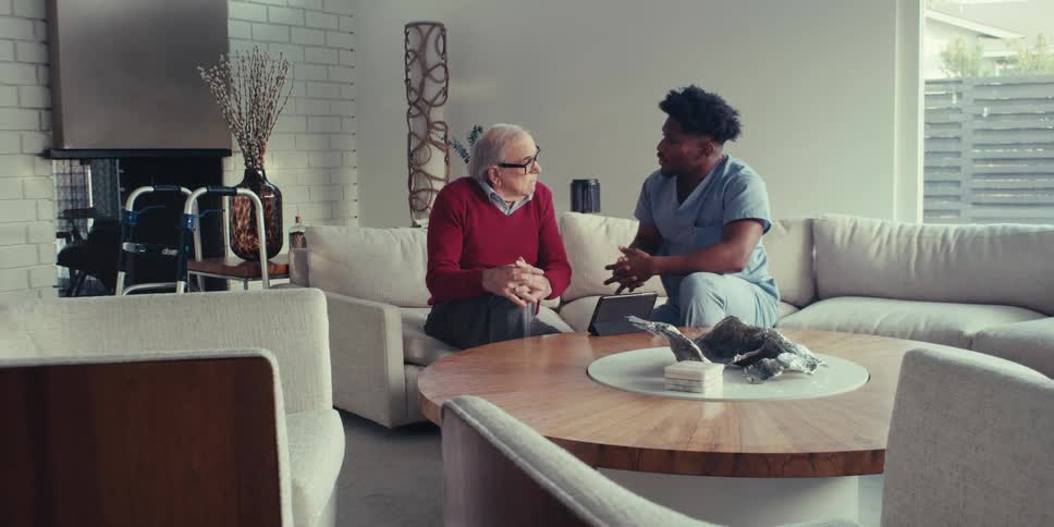 Man talking to an elderly man in front of a tablet