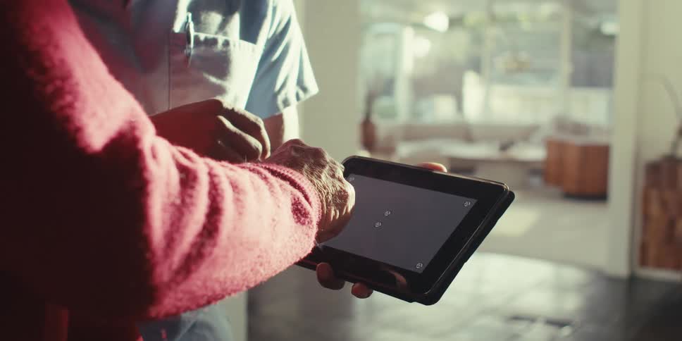 Hand of an elderly person interacting with a tablet held by another person