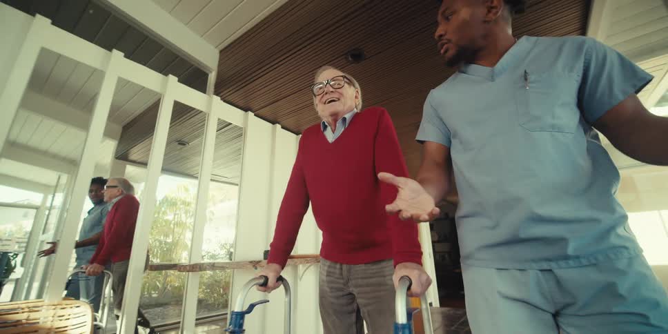 Cheerful elderly man walking next to a nurse