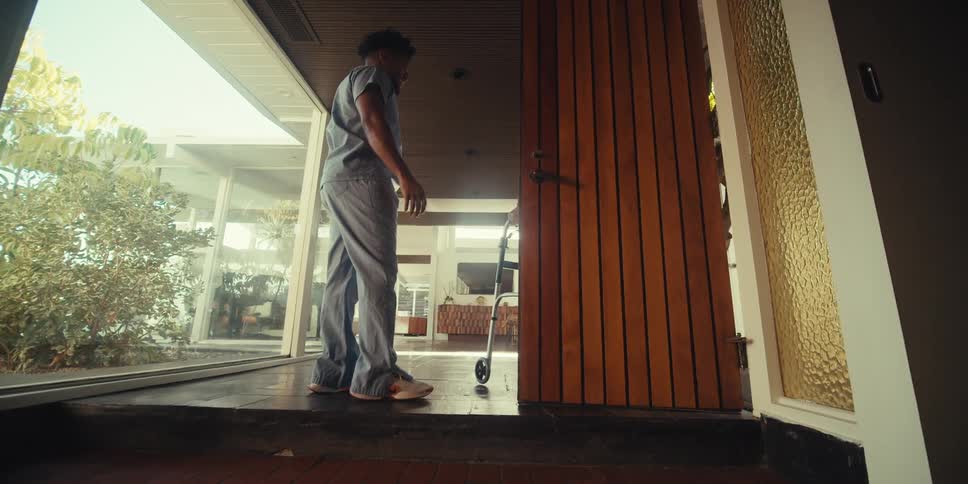 Nurse holding the door for an elderly man to enter