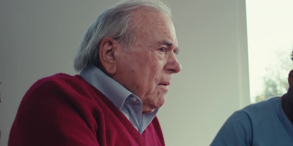 Portrait of an elderly man sitting next to another person