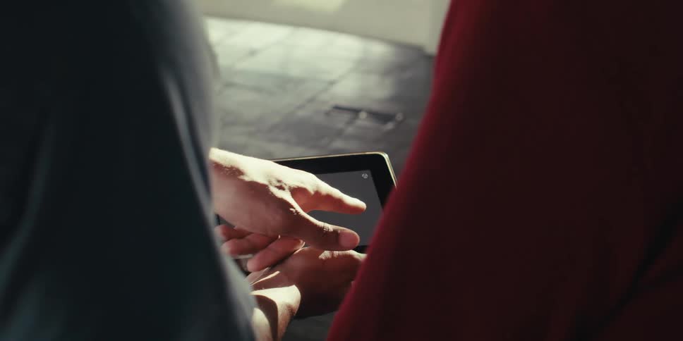 Hands of two people interacting with a tablet