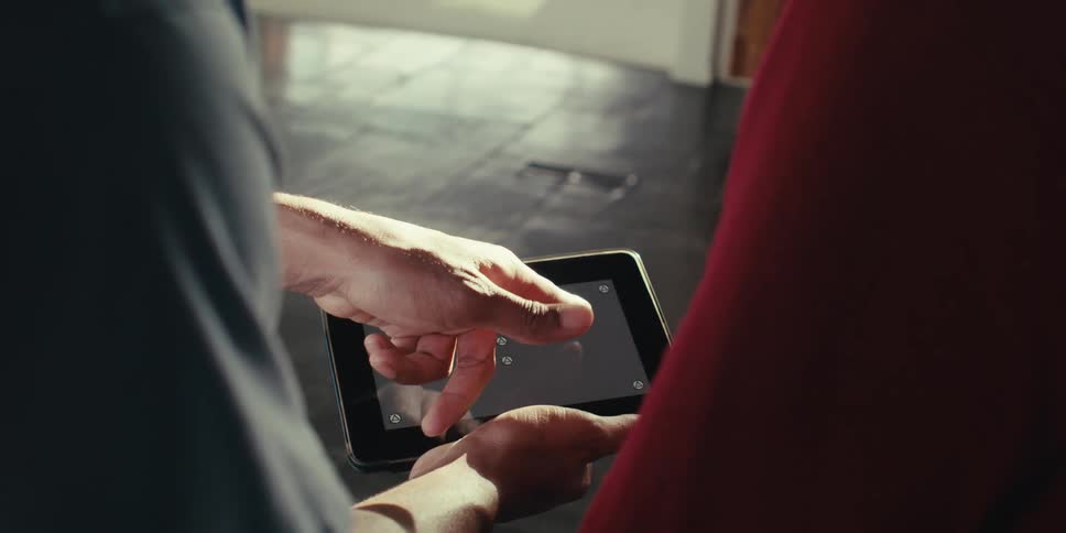 Closeup of two people pointing and interacting with a tablet that has a gray replaceable screen