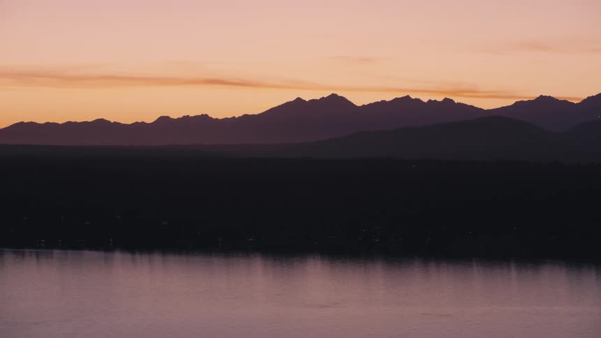 The rising sun reflects on the water by the mountains