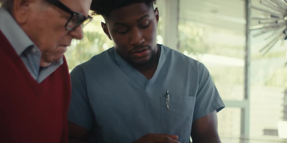Nurse talking to an elderly man in an indoor space