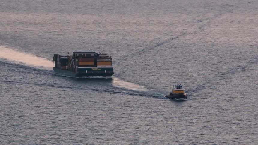 A tug boat is dragging cargo containers
