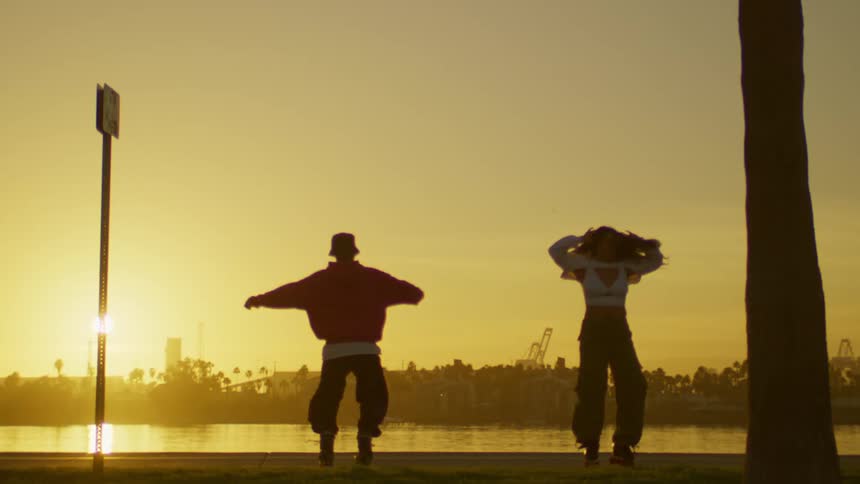 Man and woman spinning on roller skates by a lake