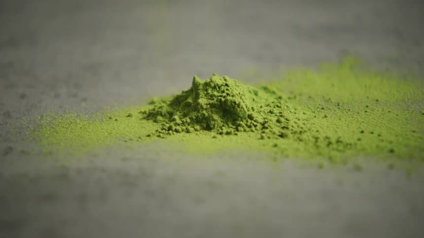 A closeup shot of vibrant green matcha powder shows its fine texture