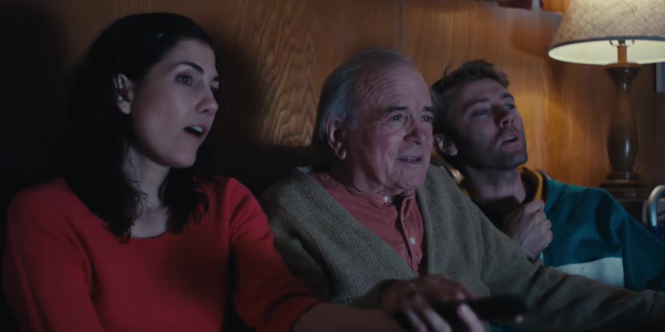 People talk while watching a television in a dimly lit living room