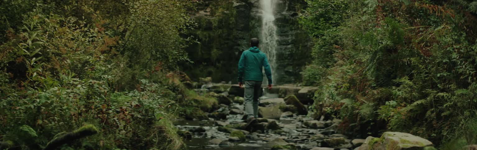 A man walks towards the small waterfall