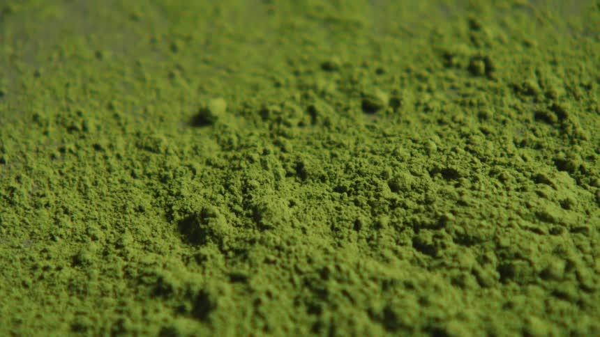 A closeup shot of vibrant green matcha powder shows its fine texture