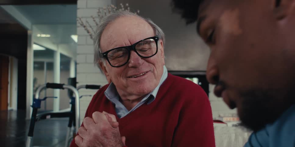 Elderly man sitting talking to a nurse next to him