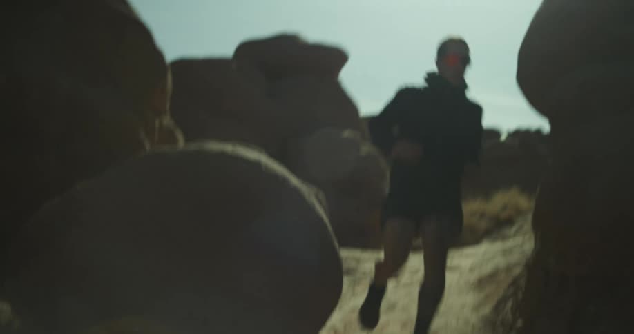 A man is running past the large boulders