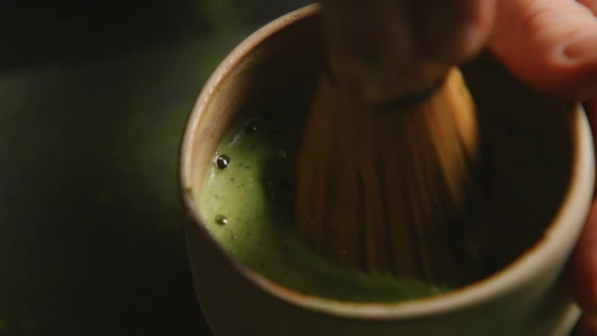A person uses a small whisk to mix the drink