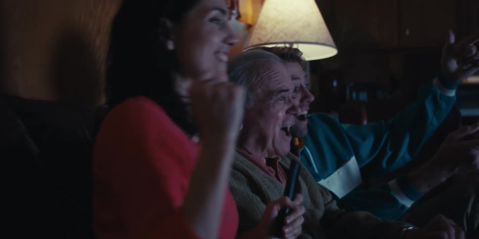 A family is sitting on a couch at home having fun while watching television