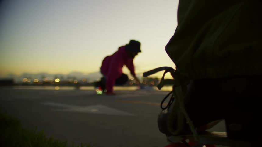 Closeup of a person dancing on roller skates spinning and maneuvering on a paved surface at dusk