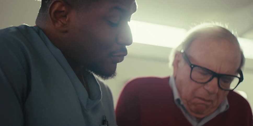 A nurse has a discussion with a man while showing him a tablet