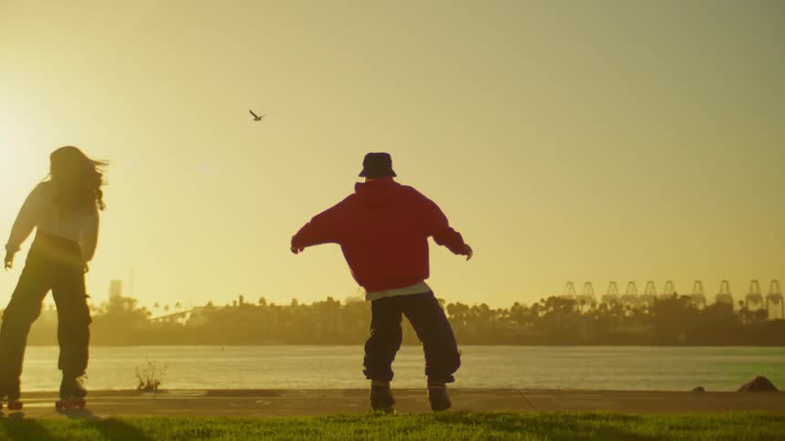 Man and woman on roller skates dancing by a lake in the late afternoon