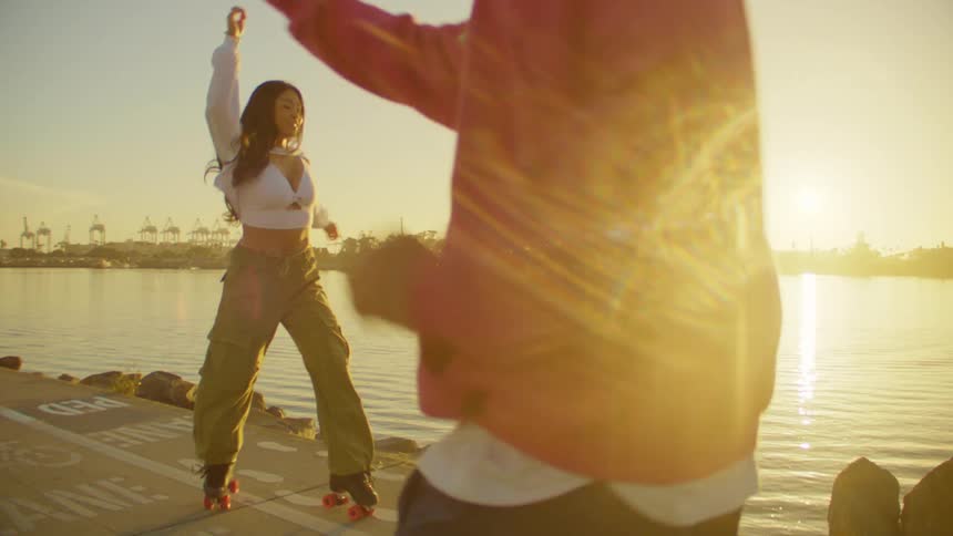 Two people dancing on roller skates by a lake