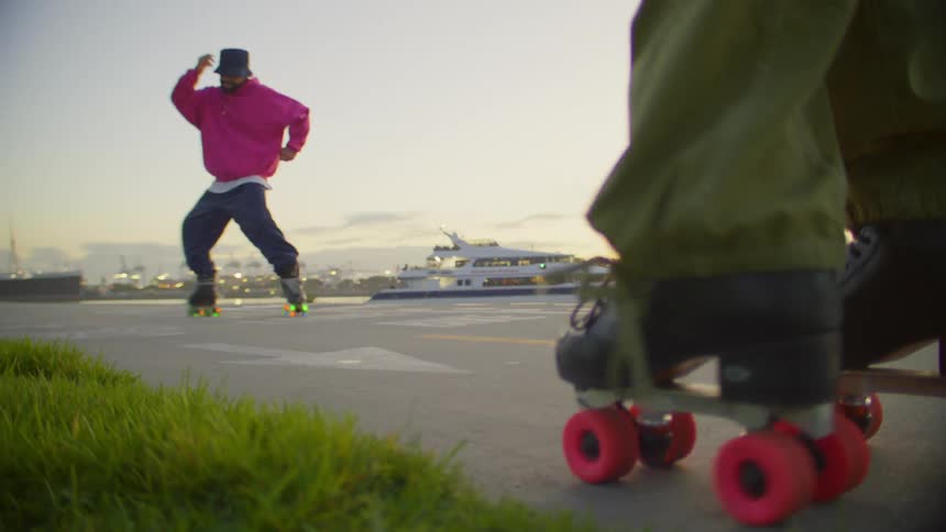 A yacht passes by a man dancing with lit roller skates