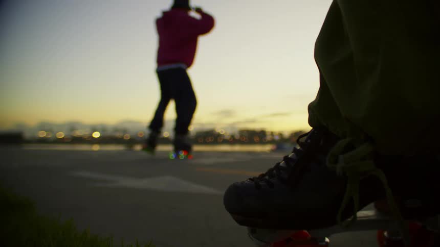 People roller blade on the road after dusk
