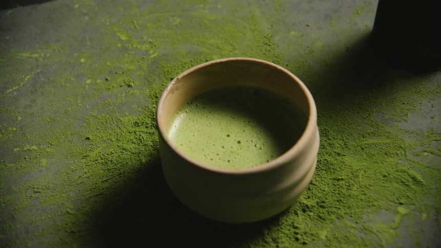 A person puts down a cup of green tea in a pile of powder